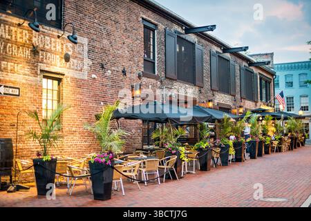 Virtue Feed and Grain Restaurant Outdoor Seating Alexandria Virginia // ALEXANDRIA, Virginia, Vereinigte Staaten – im Restaurant Virtue Feed and Grain können Sie im historischen Viertel der Altstadt von Alexandria im Freien speisen. Das Restaurant befindet sich in einem renovierten Lagerhaus aus dem 19. Jahrhundert, das einst als Futtermittel- und Getreidelager an der 106 South Union Street diente. Das Hotel liegt nur einen Block vom Potomac River Uferpromenade entfernt und bietet Gästen die Möglichkeit, Mahlzeiten zu genießen und gleichzeitig den historischen Charme der Altstadt von Alexandria zu erleben. Die Sitzplätze auf der Terrasse erweitern die Essenskapazität des Restaurants auf bis zu 10 Stockfoto