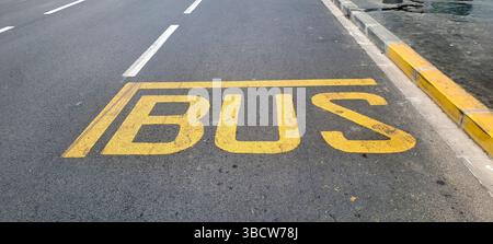 Gelbe Markierung der Bushaltestelle auf der Asphaltstraße, die den für Busse vorgesehenen Haltebereich anzeigt Stockfoto