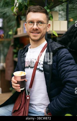 Junger glücklicher Kerl, der Kaffee trinkt Stockfoto