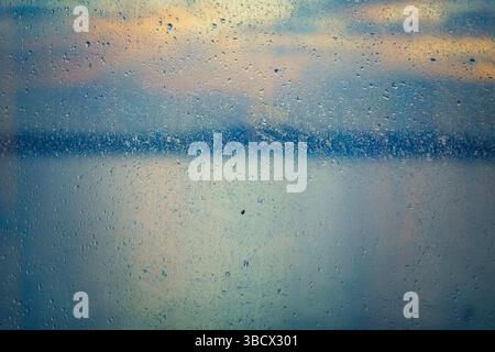Regentropfen am Fenster mit Blick auf das Wasser im Hintergrund, Puget Sound, Washington State, USA. Stockfoto