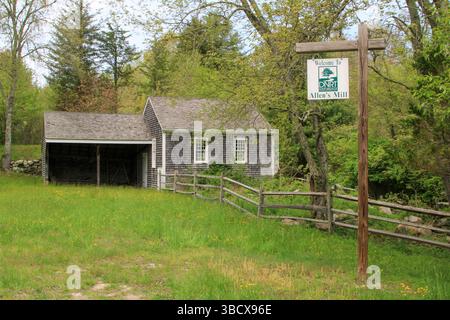 Historisches New England Cape Home aus den 1700er Jahren mit braunem Schindelholzzaun und Steinmauer Stockfoto