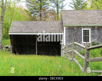 Historisches New England Cape Home aus den 1700er Jahren mit braunem Schindelholzzaun und Steinmauer Stockfoto