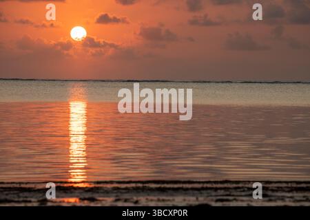 Farbenfroher Sonnenaufgang über der nordöstlichen Küste von Sansibar Island, Tansania. Winzige Wellen welken über die Meeresoberfläche. Stockfoto