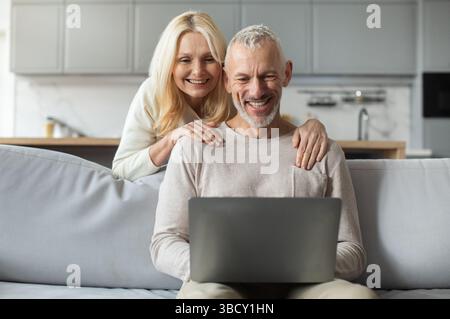 Paare genießen eine gute gemeinsame Zeit, während sie zu Hause ein Notebook verwenden Stockfoto