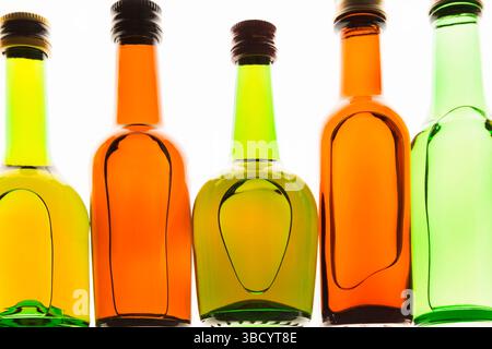 Farbenfrohe, aufrechte Miniaturflaschen in verschiedenen Formen auf weißem, durchscheinendem Hintergrund. Stockfoto