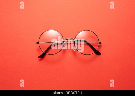 Gläser in rundem, dünnem Metallrahmen isoliert auf roter Oberfläche. Stockfoto