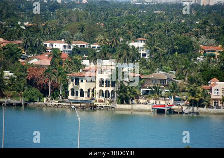 Luxuriöse Villen am Wasser, umgeben von Palmen entlang der Küste von Miami, an einem sonnigen Tag vom Wasser aus gesehen Stockfoto