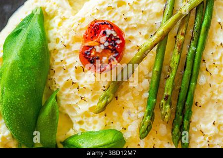 Omelett mit gebackenem Spargel, Tomaten und Basilikum. Nahaufnahme, Hintergrund. Zur Verwendung in Menüs und Bannern. Das Konzept eines leckeren und gesunden Frühstücks. Stockfoto