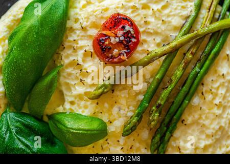 Omelett mit gebackenem Spargel, Tomaten und Basilikum. Nahaufnahme, Hintergrund. Zur Verwendung in Menüs und Bannern. Das Konzept eines leckeren und gesunden Frühstücks. Stockfoto