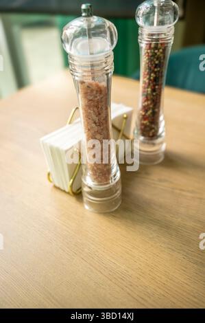 Salz- und Pfeffermühlen auf einem Holztisch und Papierservietten Stockfoto