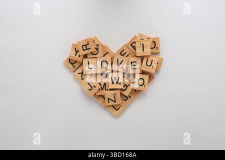 Scrabble-Fliesen in Herzform mit dem Wort „LIEBE“ als Mittelpunkt. Stockfoto