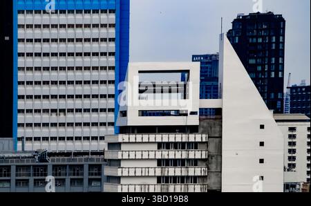 Ein modernes weißes Gebäude mit geometrischen Formen in einer urbanen Umgebung. Umgeben von hohen Türmen spiegelt dieses architektonische Gebäude zeitgenössisch wider Stockfoto