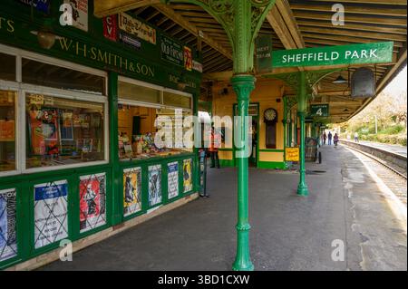 Vintage-Szene am Bahnsteig Sheffield Park an der Bluebell Railway Line mit altmodischem W.H. Smith Kiosk und Werbung. Sussex, England. Stockfoto