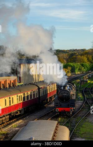 Eine Dampflokomotive rangiert Personenwagen auf der Bluebell Railway Line am Bahnhof Sheffield Park in East Sussex, England. Stockfoto