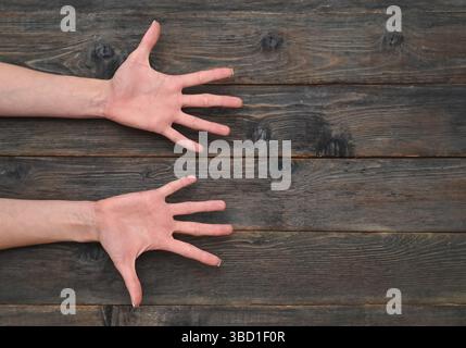 Elegante Frauenhände liegen auf Holzoberfläche. Zarte Frauenhände auf rustikalem Holztisch. Ausgestreckte Finger der Frauenhand auf offenen Handflächen Stockfoto