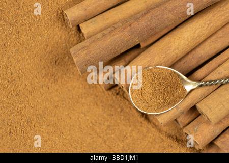 Gemahlenes Zimtgewürz in einem Löffel und Zimtstangen, Draufsicht Stockfoto