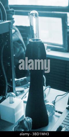 Art Object Lampe mit einer leuchtenden Glühlampe in Form einer menschlichen Hand, die auf einem 3D-Drucker gedruckt wird. Modellprototyp menschlicher Hand, gedruckt auf 3D-Drucker aus geschmolzenem Kunststoff, der auf dem Tisch steht. Blaue Farbe Stockfoto