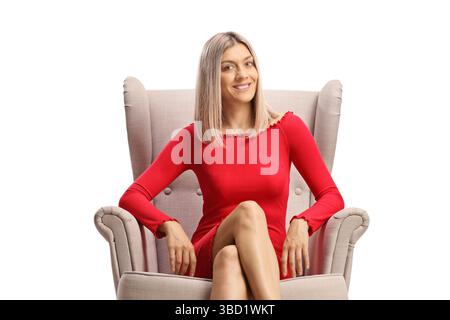 Junge Frau in einem roten Kleid, die in einem Sessel auf weißem Hintergrund sitzt Stockfoto