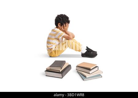 Trauriges Kind, das auf dem Boden sitzt, mit Büchern isoliert auf weißem Hintergrund Stockfoto