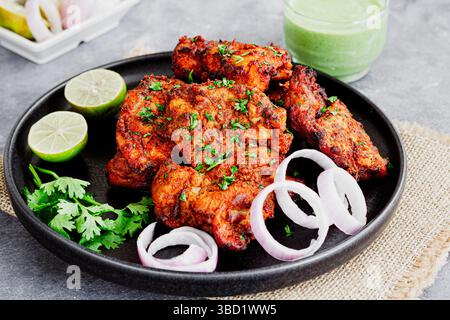 Tandoori Hähnchenschenkel mit Zitrone, Zwiebeln und grünem Chutney garniert mit frischem Koriander Nahaufnahme Stockfoto