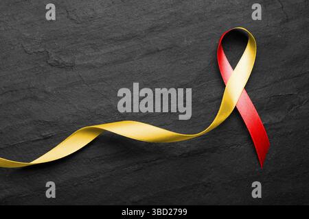 World Hepatitis Day. Gelb-rotes Alarmband auf schwarzem Tisch, Draufsicht Stockfoto