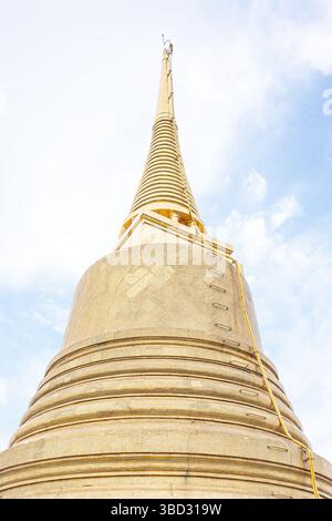 Ein minimalistisches Foto der goldenen Pagode am Wat Saket (Goldener Berg) in Bangkok, Thailand, aufgenommen aus einem niedrigen Winkel vor einem klaren blauen Himmel. Stockfoto