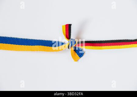 Die Flagge der Ukraine und Deutschlands in einem Knoten auf weißem Hintergrund, ein Symbol für Freundschaft und Partnerschaft zwischen Ländern Stockfoto