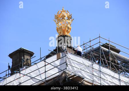 Goldene Dekoration mit Adlern und Gerüsten mit einem Mann auf dem Dach des Königspalastes in Amsterdam, Niederlande, Mai 2025. Stockfoto