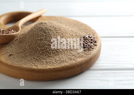 Leinsamenmehl und Löffel mit Samen auf weißem Holztisch, Nahaufnahme Stockfoto
