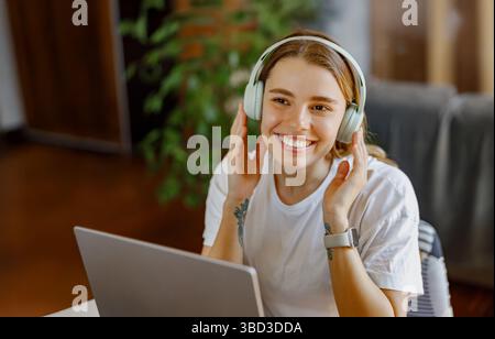 Eine glückliche junge Frau genießt es, Musik mit ihren Kopfhörern zu hören, während sie sich zu Hause entspannt Stockfoto