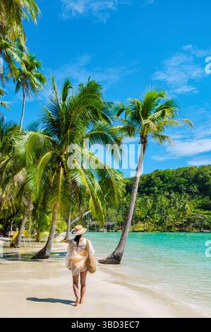 Weicher Sand berührt sanft die Küste, während ein Reisende entlang des unberührten Strandes von Koh Koods spaziert. Üppige Palmen wiegen in der warmen Brise und laden zur Entspannung und Gelassenheit im tropischen Paradies Thailands ein. Stockfoto
