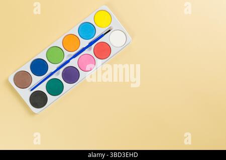 Draufsicht auf Aquarell und Pinsel auf gelbem Hintergrund. Malerei, Kunst, Kopierraum, flache Lay. Stockfoto