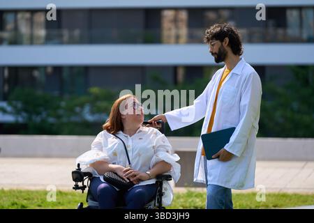 Arzt, der behinderte Frau im Rollstuhl im Park tröstet - Rollstuhl- und Behindertenkonzept Stockfoto