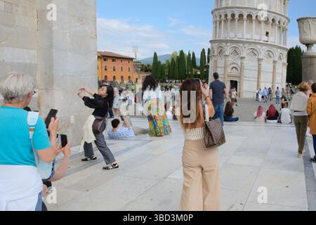 Touristen geben sich vor, um Fotos auf der berühmten Piazza dei Miracoli (Platz der Wunder) neben dem Schiefen Turm von Pisa in der Toskana, Italien zu machen Stockfoto