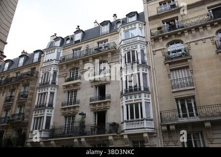 Ein wunderschön gestaltetes mehrstöckiges europäisches Wohngebäude verfügt über kunstvoll verzierte Balkone mit schmiedeeisernen Geländern, große Fenster und helle Farben Stockfoto