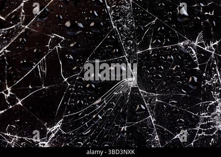 Wasser bedeckt zerbrochenes Glas mit vielen Schäden auf schwarzem Hintergrund, nasses, dünnes Glas in viele Stücke gebrochen Stockfoto