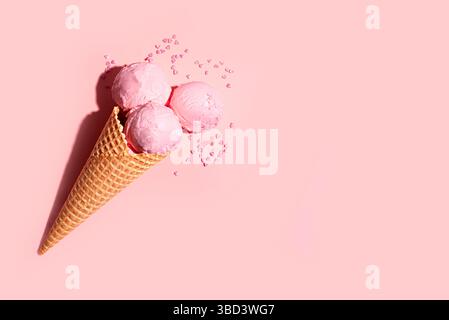 Erdbeerrosa Eiskugeln mit herzförmigen Streuseln in Waffelkegel auf rosa Hintergrund, kreatives Design mit hartem Licht, Kopierraum. Sommer Be Stockfoto