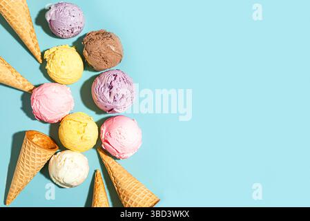 Verschiedene Eiskugeln und Waffelkegel kreativ flach auf blauem Hintergrund, Draufsicht, Kopierraum. Verschiedene Eissorten oder Eis-Design, trendig Stockfoto