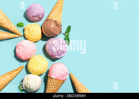 Verschiedene Eiskugeln und Waffelkegel kreatives Layout auf blauem Hintergrund, Draufsicht, Kopierraum. Verschiedene Eissorten oder trendiges Eis-Design Stockfoto
