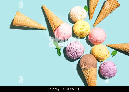 Verschiedene Eiskugeln und Waffelkegel kreatives Layout auf blauem Hintergrund, Draufsicht, Kopierraum. Verschiedene Eissorten oder Eis-Design, trendige Ba Stockfoto