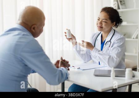 Die Lächelnde Schwarze Ärztin Demonstriert, Wie Sie Männlichen Patienten Medikamente Verschreibt Stockfoto