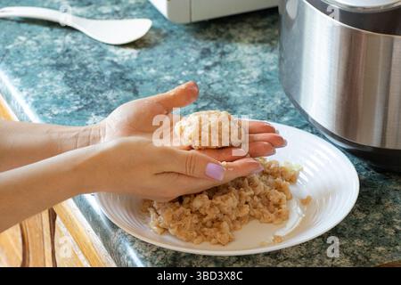 Das Mädchen machte ein Schnitzel aus rohen gehackten Hühnern und hält es in der Küche, kocht Schnitzel Stockfoto