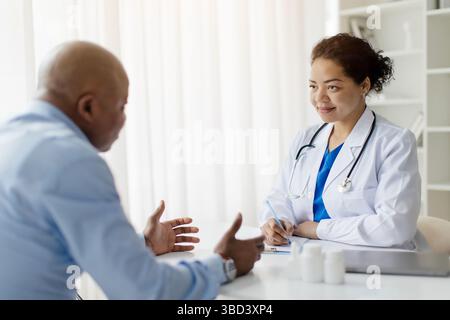 Lächelnde Schwarze Ärztin In Uniform Beratung Männlichen Patienten Während Des Treffens In Der Klinik Stockfoto