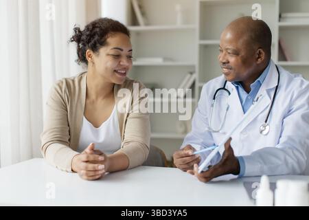 Schwarzer Arzt Zeigt Clipboard Mit Testergebnissen Neugierigen Weiblichen Patienten Stockfoto