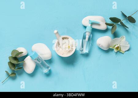 Komposition mit Kosmetikprodukten, Kursteinen und Eukalyptuszweigen auf farbigem Hintergrund Stockfoto