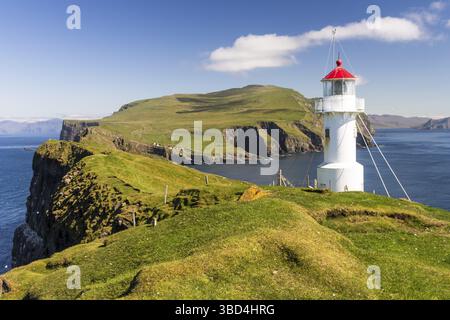 Kleiner, weißer Leuchtturm mit rotem Dach, auf Mykinesholmur, einer Insel, die an die Insel Mykines grenzt und an einem sonnigen Augusttag mit der bea zu sehen ist Stockfoto