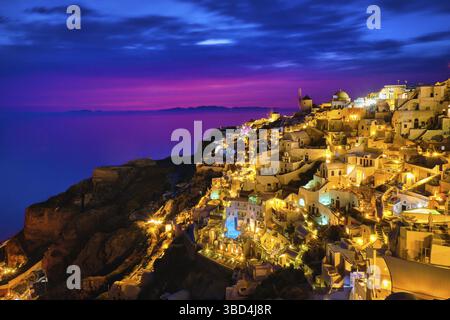 Wunderschöner Blick auf das Dorf Oia mit traditionellen weiß getünchten Häusern und Windmühlen, Insel Santorin, bei Sonnenuntergang, Griechenland. Landschaftlich reizvoller Reisehintergrund, berühmt Stockfoto