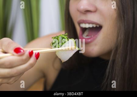 Frau, die leckeres Gunkan-Sushi isst, Nahaufnahme von Essstäbchen Stockfoto
