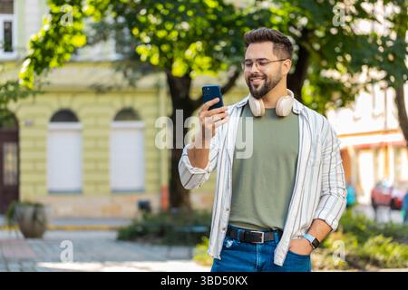 Glücklicher erfolgreicher zufriedener kaukasischer Mann junger Mann männlicher Reisender Handy-Benutzer mit Smartphone SMS Chat soziale Medien Touristen Online GPS Karte im Freien Stadt Straße. Lebensstil in der Stadt. Stockfoto