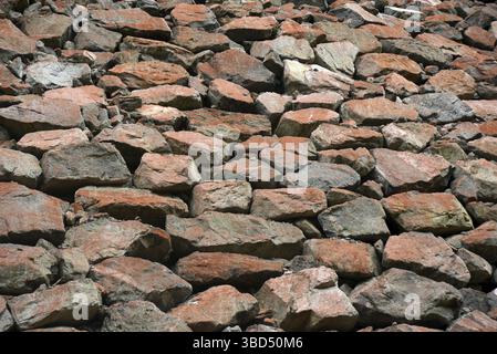Harte Felsen auf einer großen Stoppbank schaffen einen rustikalen strukturierten Hintergrund Stockfoto